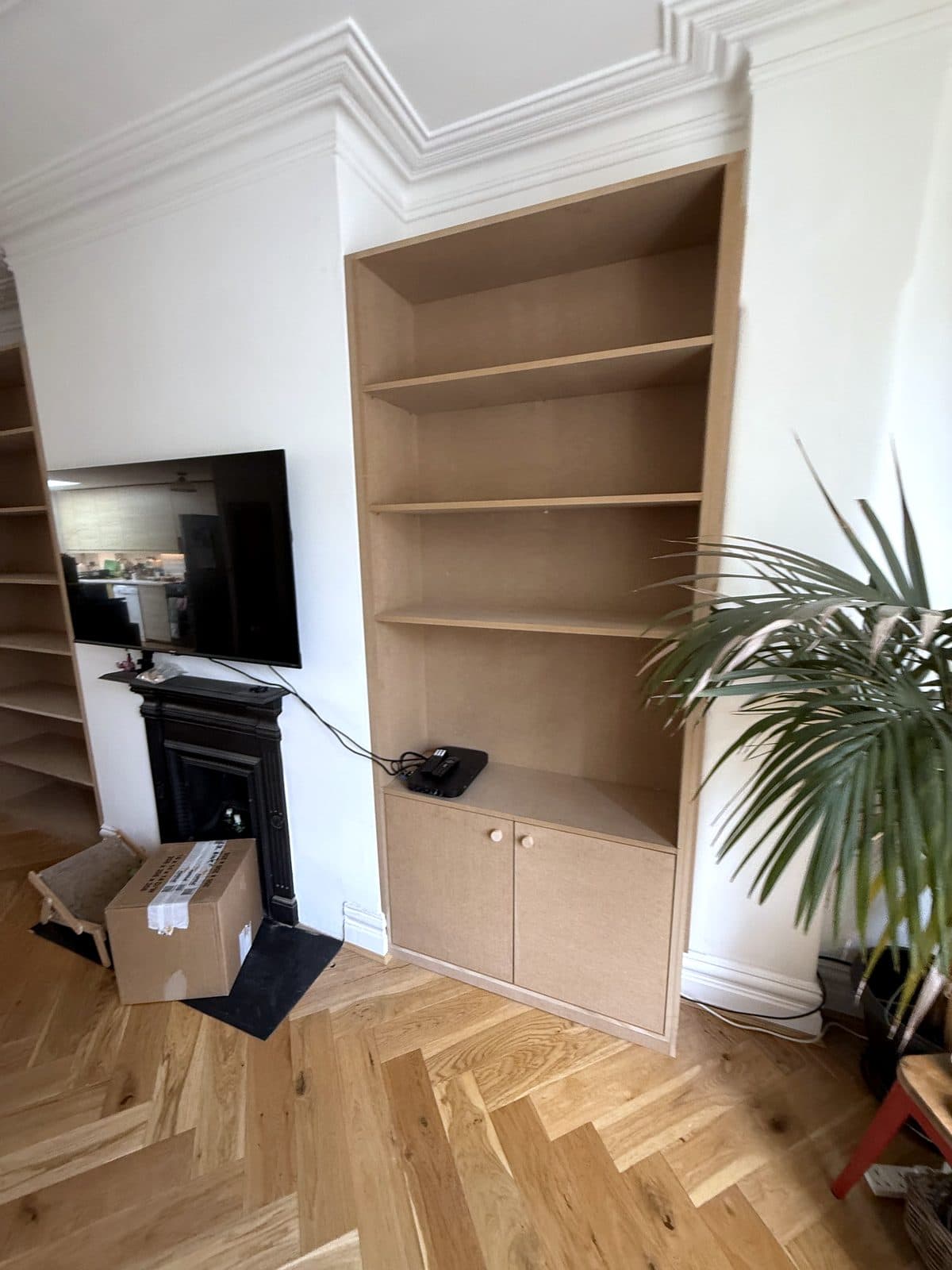 Right alcove unit with shelves over a cupboard, next to the fireplace