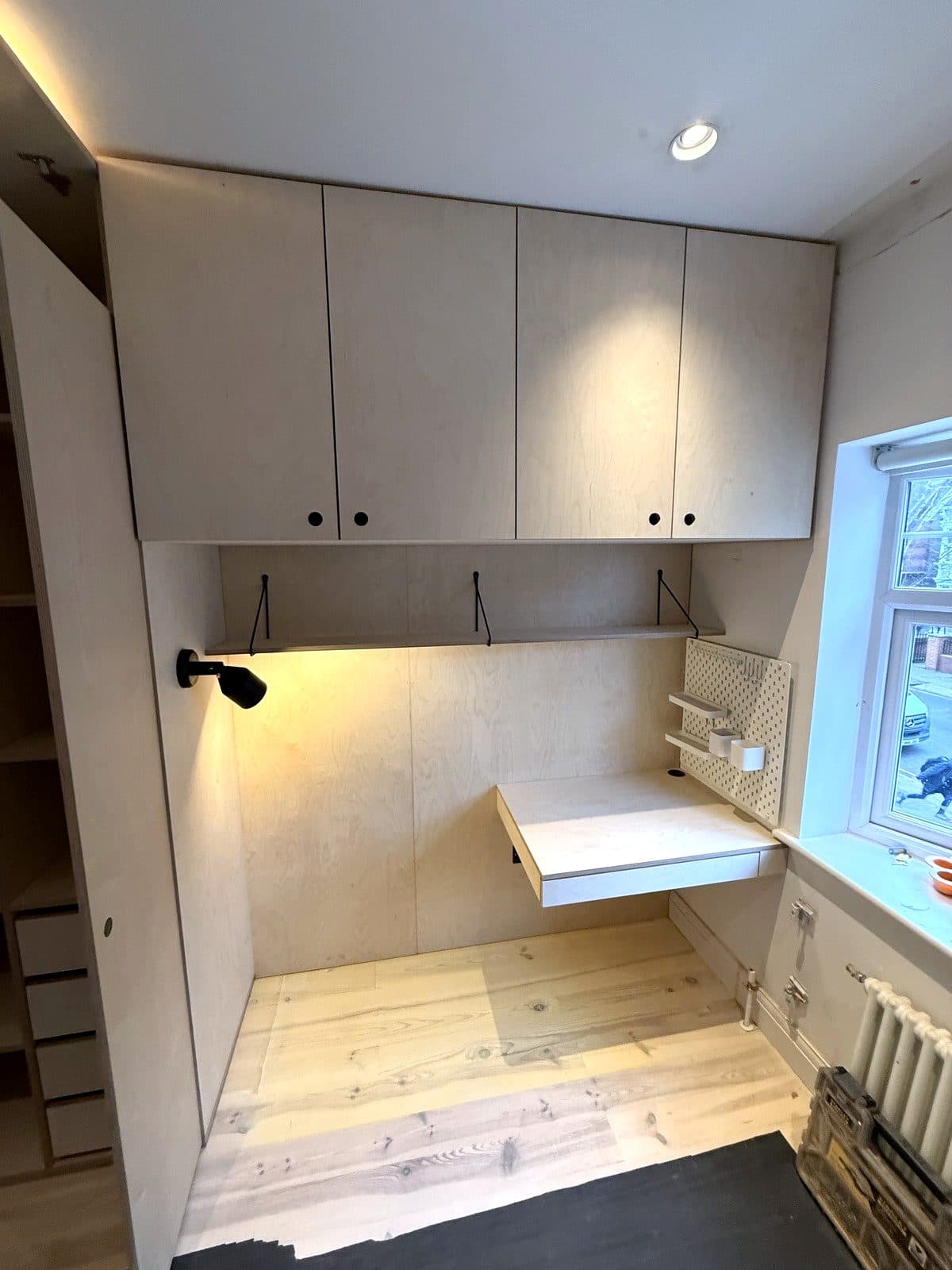 The desk under the window with cupboards above