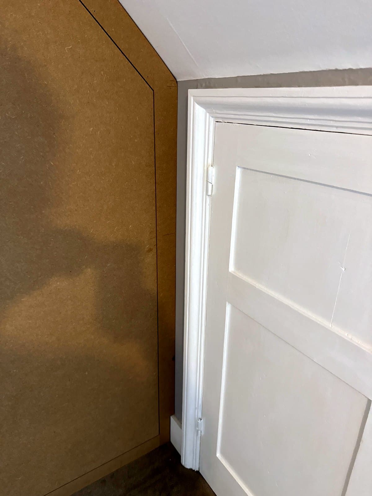 The sloped edge of the wardrobe beside the small door