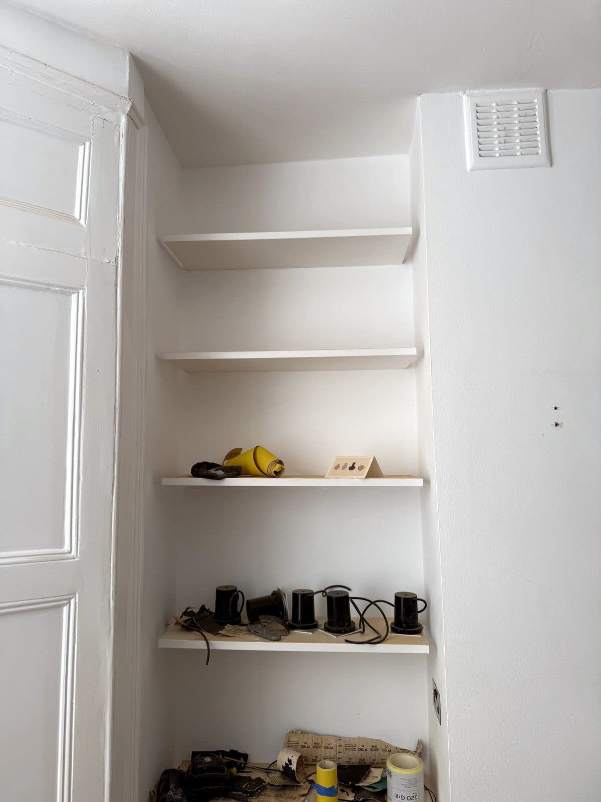 Old shelves on brackets in the alcove, covered in tools
