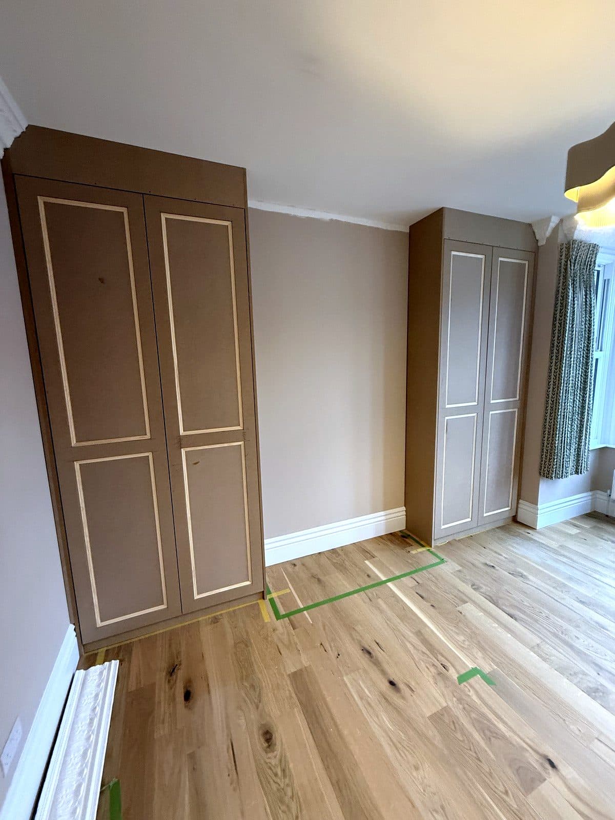 Two tall MDF wardrobes with panelled doors in the alcoves of a bedroom