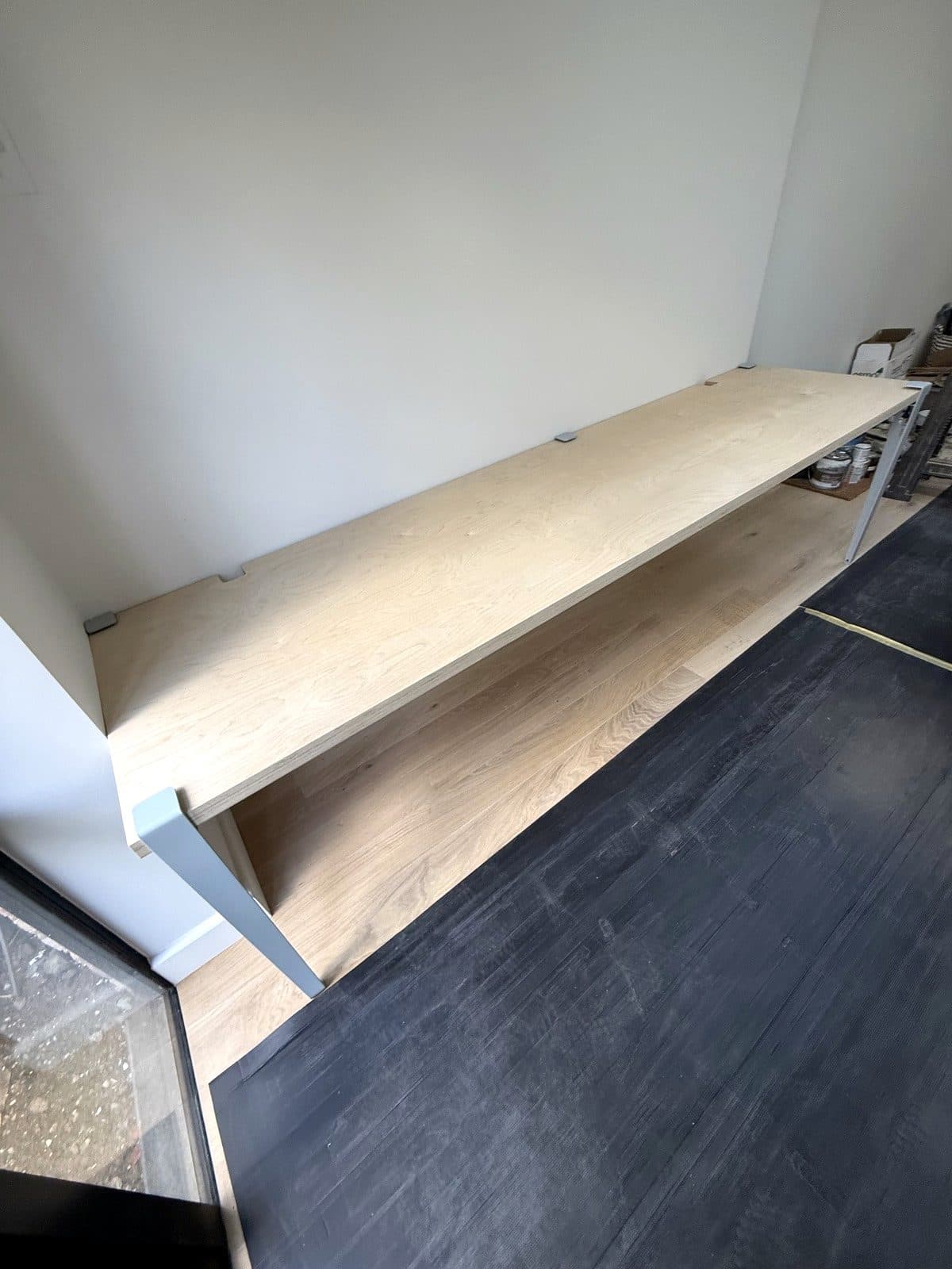 Long birch ply desk with a shelf underneath along the wall of a garden room