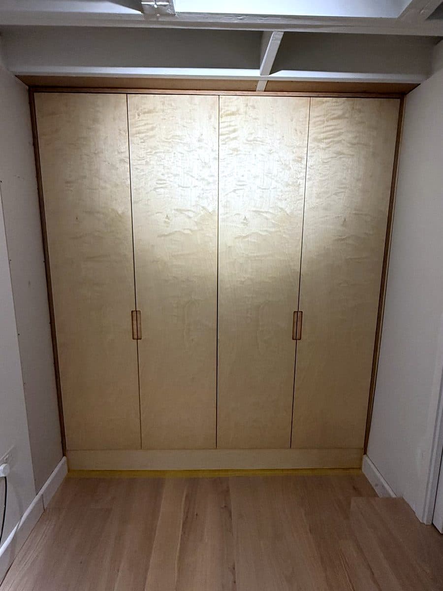 Four-door birch ply wardrobe filling a recess, with long wooden pull handles