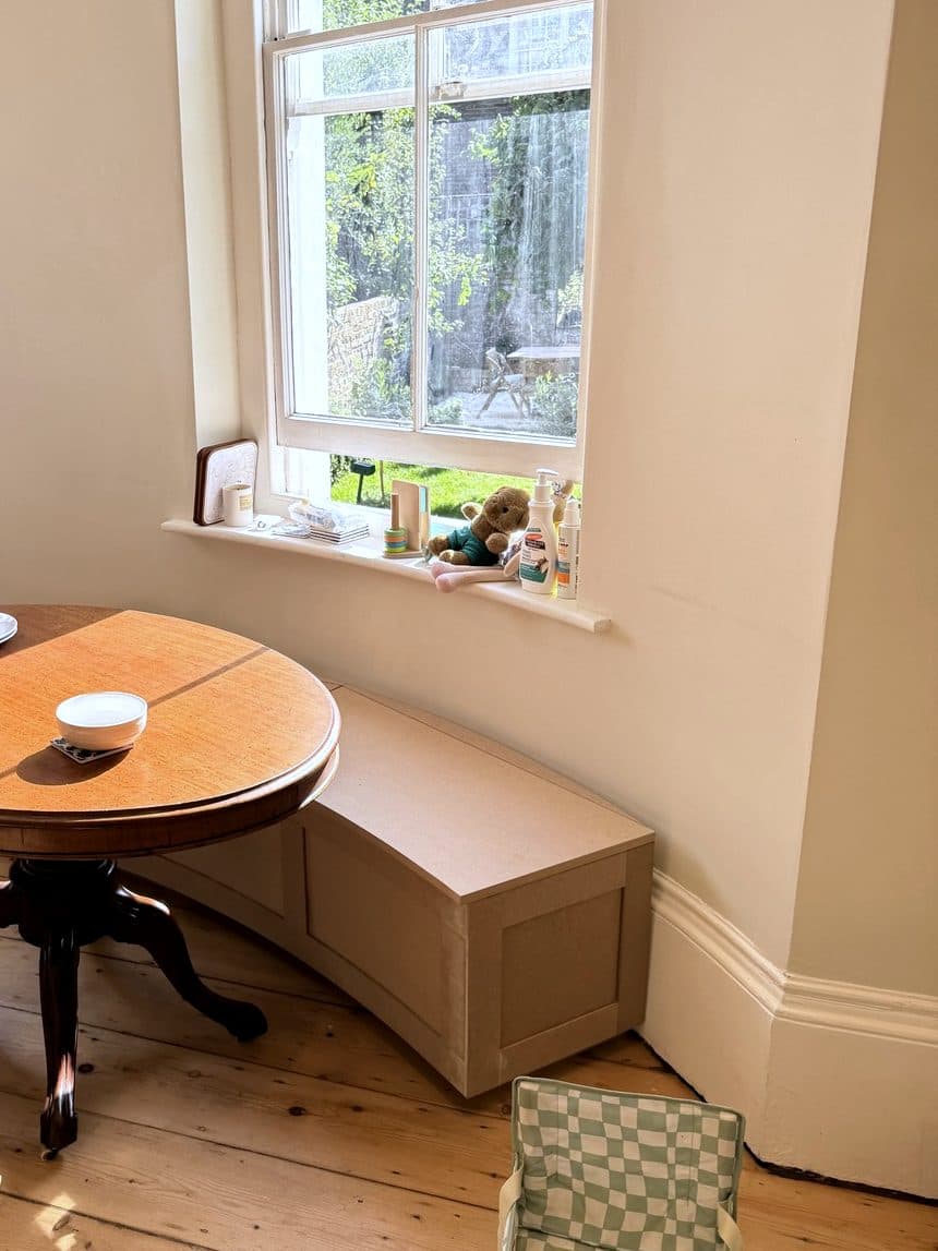 Curved MDF storage bench in a kitchen bay next to a round table