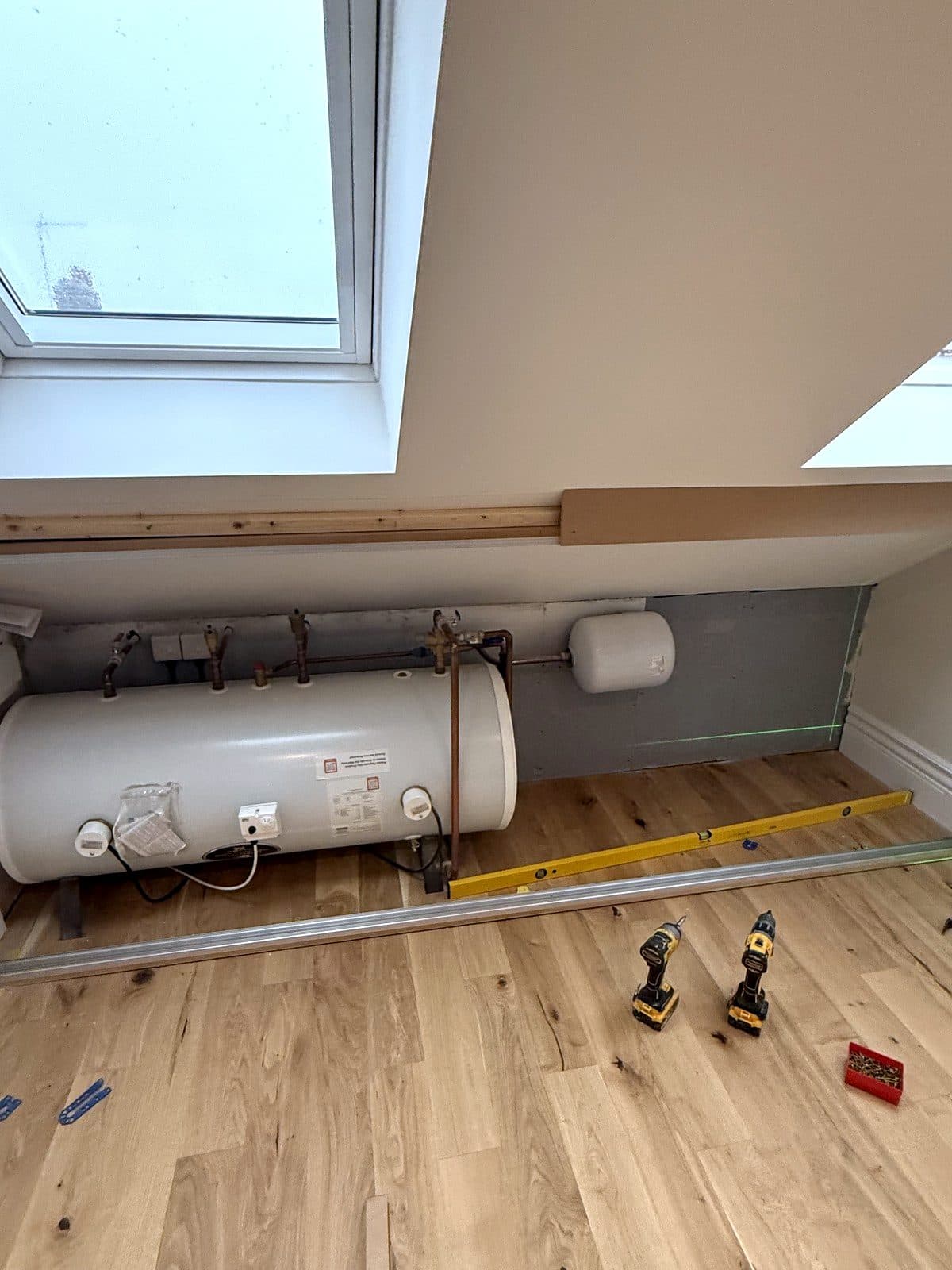 Hot water cylinder and pipework sitting in the open under the eaves