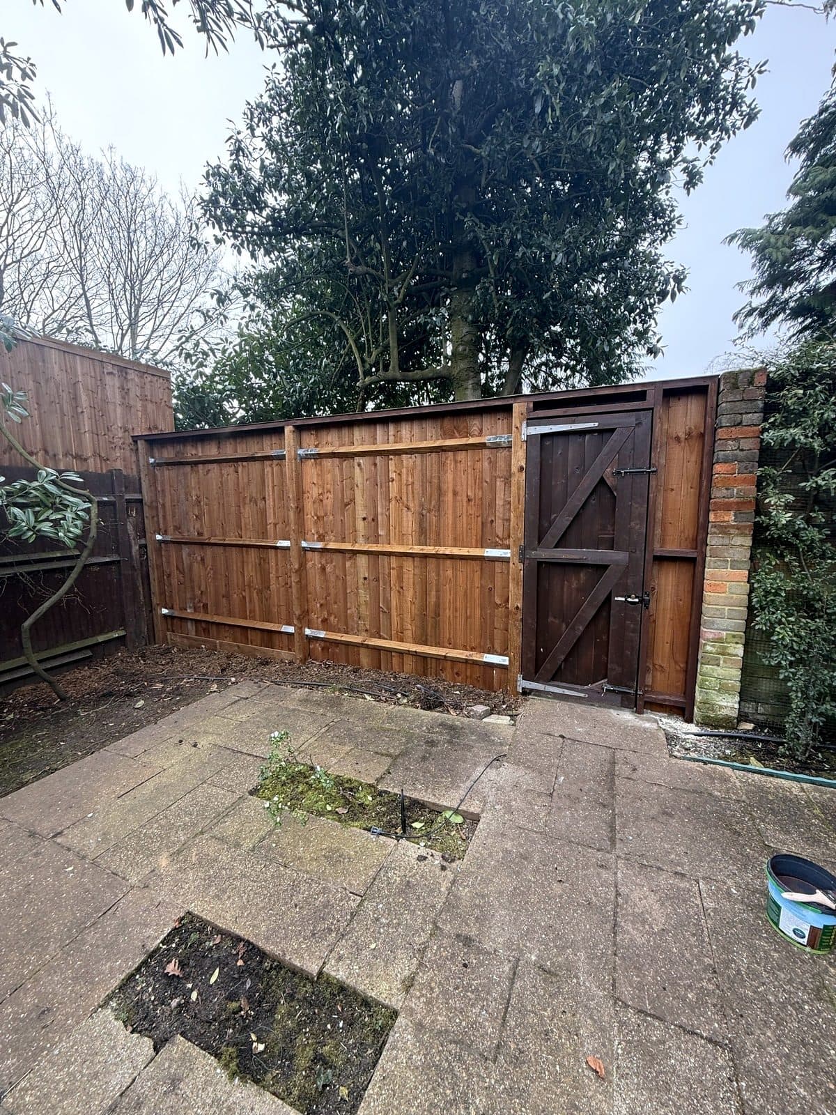 New close-board fence with a gate across the back of a patio