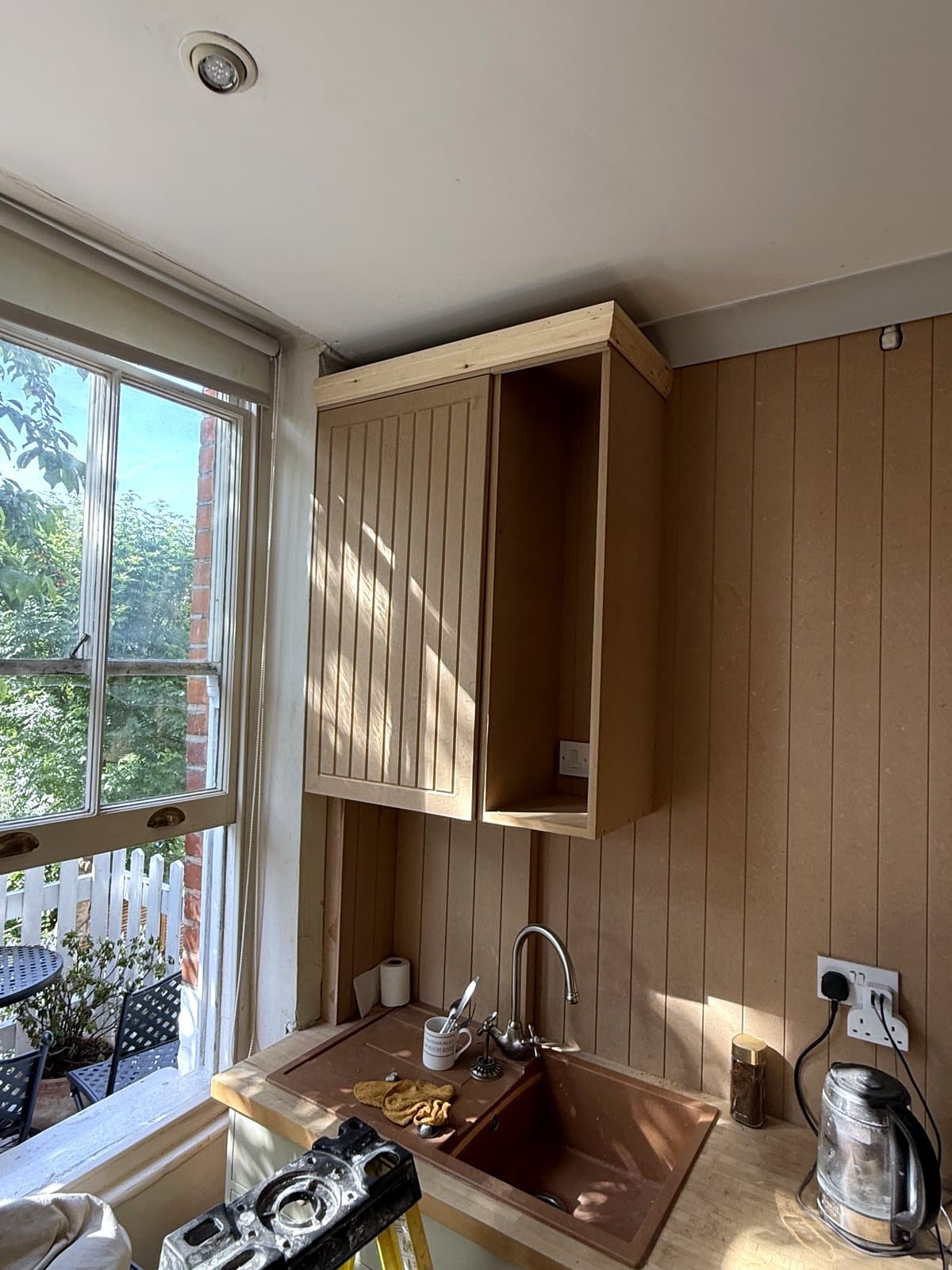 Panelled wall cupboard carcass by the window