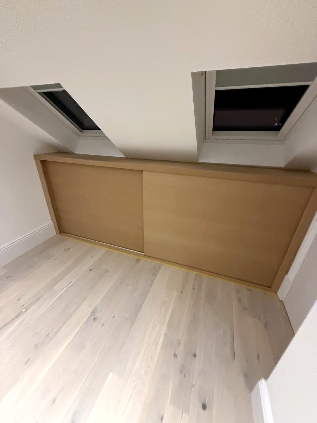 Low storage with two sliding doors under the skylights of a loft room