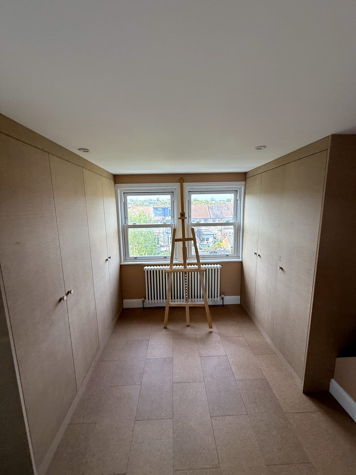 Loft room with MDF wardrobes along both sides and a window at the end