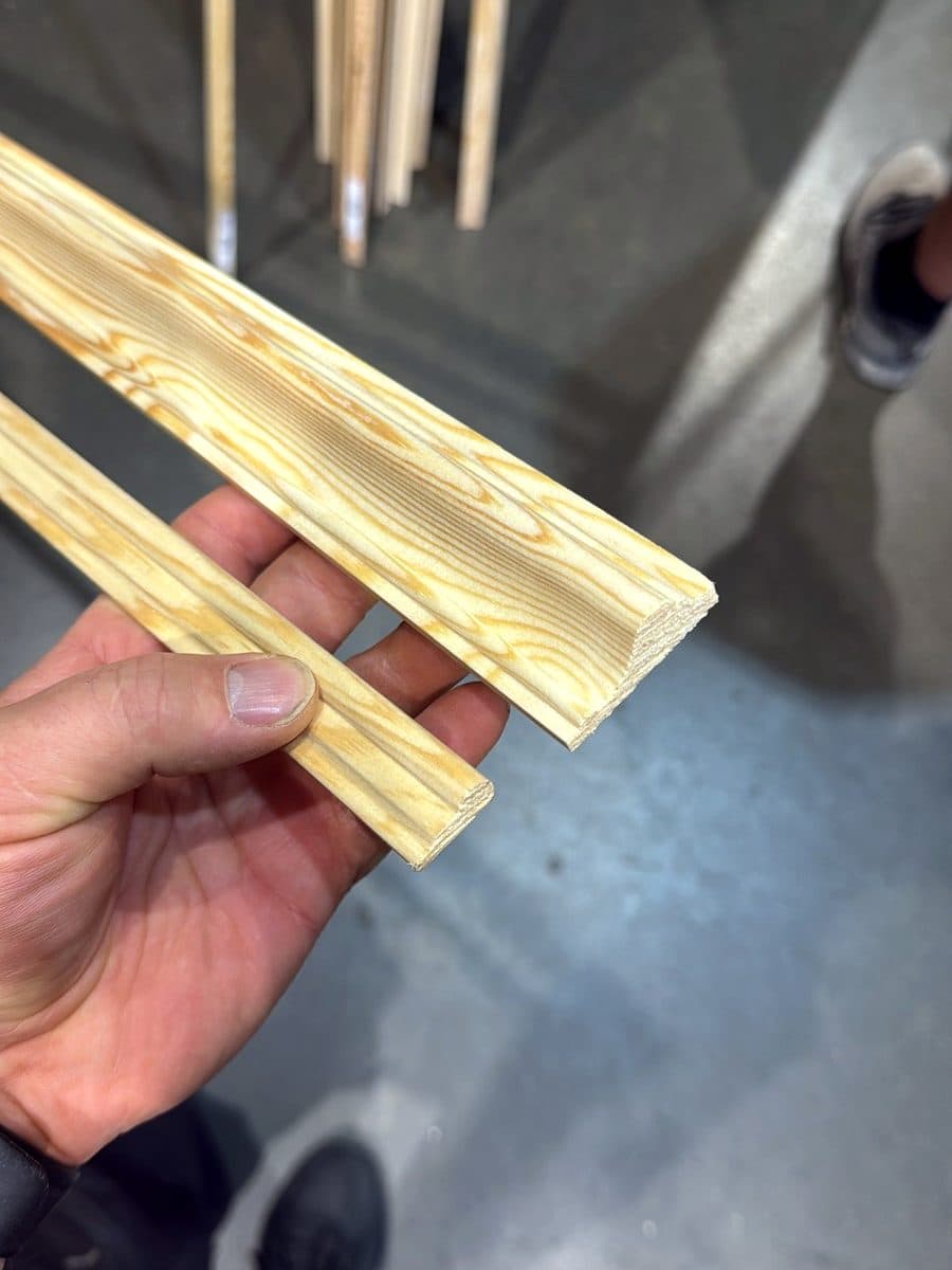 Two lengths of pine moulding held in a hand at the timber merchant