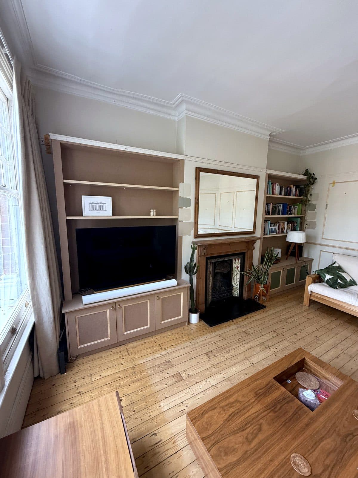 Living room with an MDF TV unit in the left alcove, the fireplace and mirror in the middle and a bookcase in the right alcove
