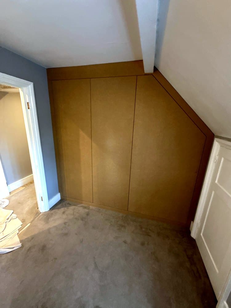 The same corner after: a flat MDF wardrobe front with three doors