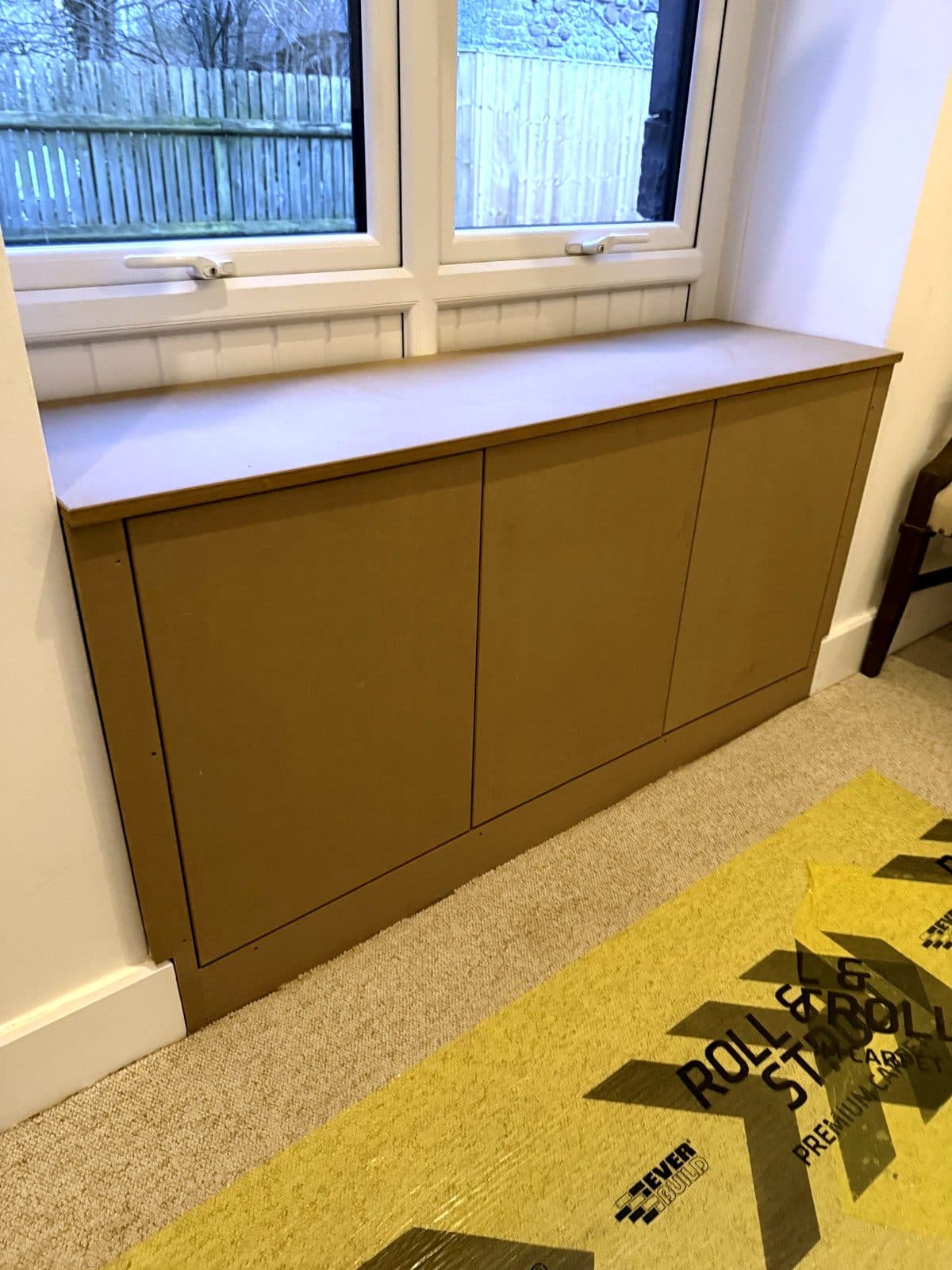 Painted window seat cupboards with flat doors under a window