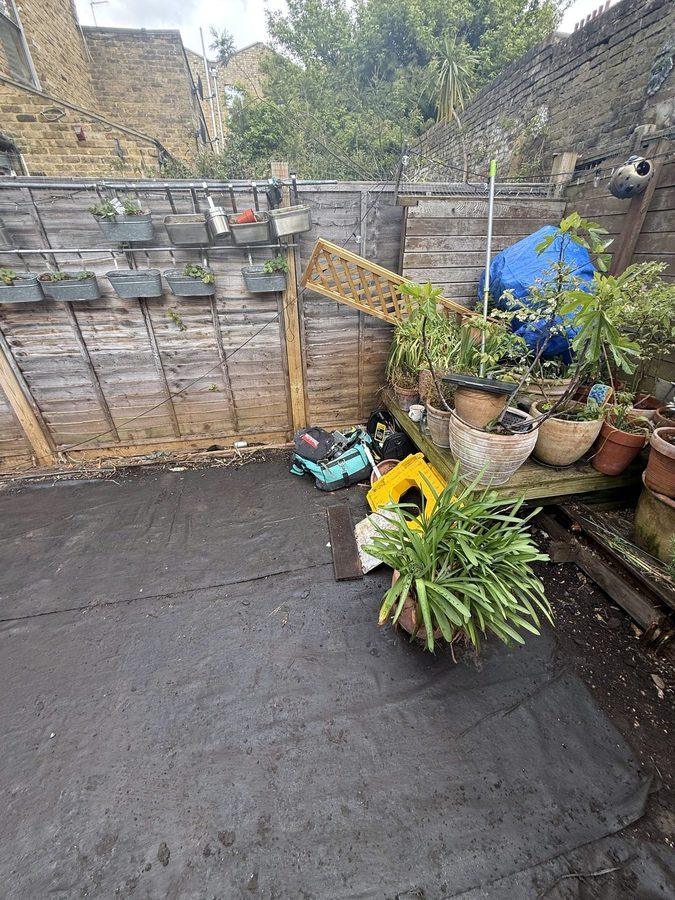 Weed membrane laid across the courtyard, with the plants pushed into one corner