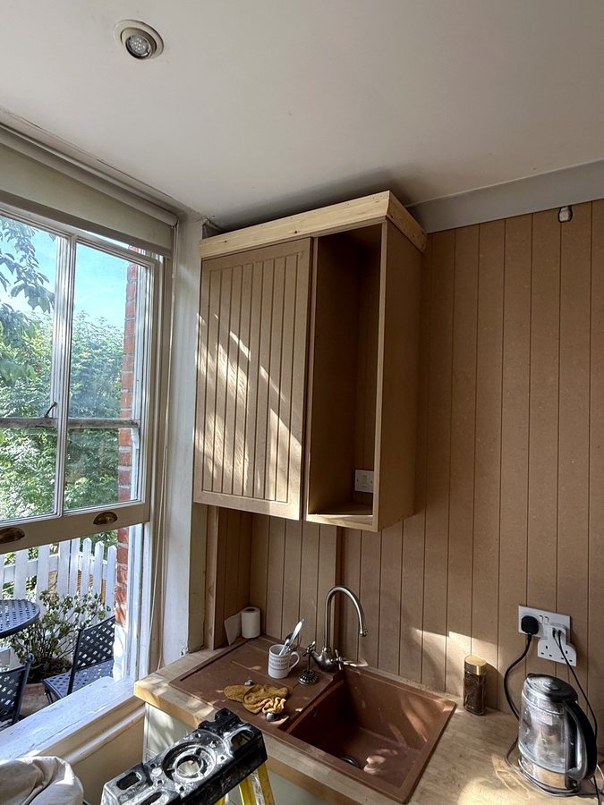The wall cupboard by the window, with one door on