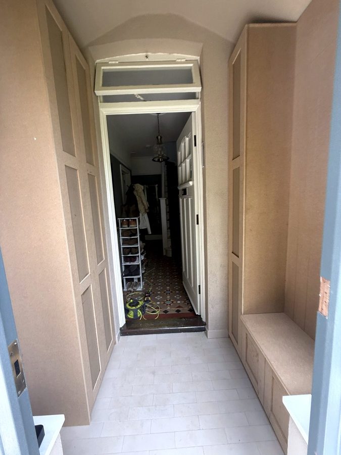 Looking through the porch to the hall door: tall cupboard on the left, shoe cupboard and bench on the right