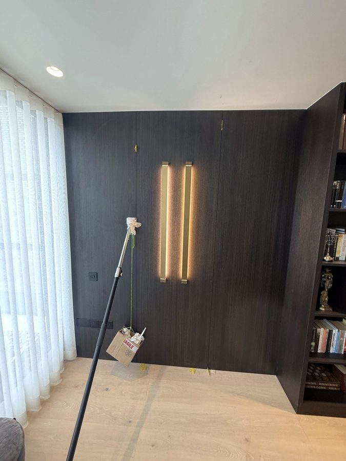 The panelled wall with the two brass strips lit