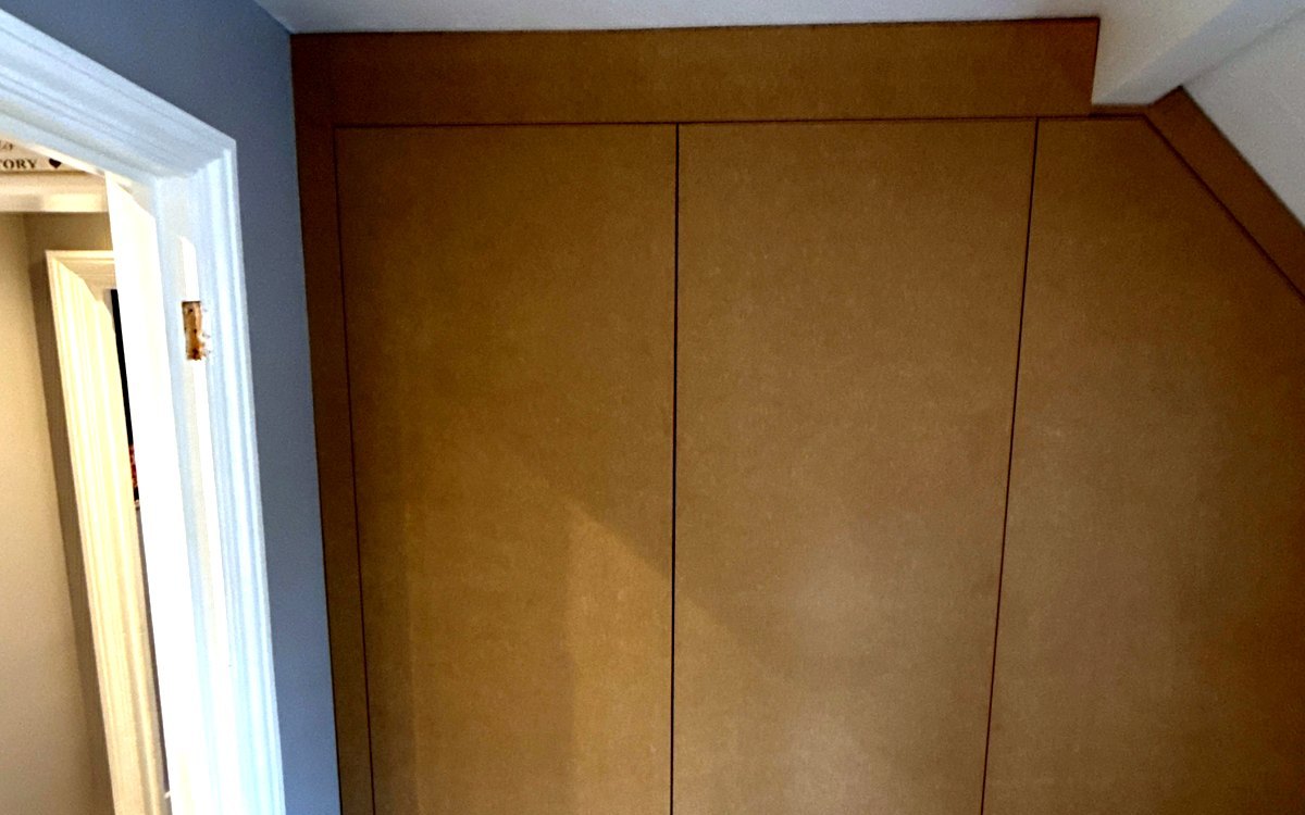 A made-to-measure wardrobe built round timber beams in a Hatfield loft